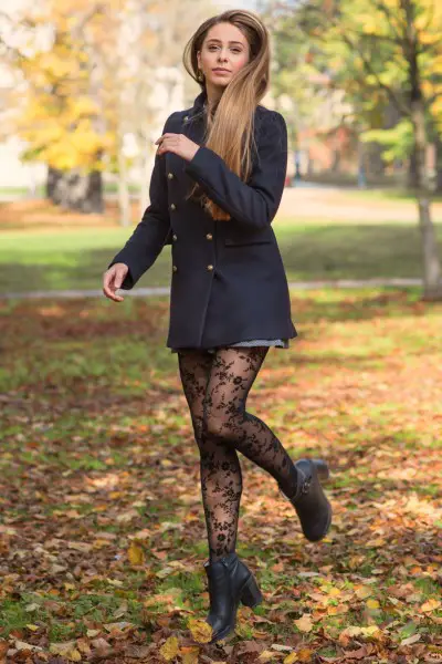 A woman wears black ankle cowboy boots with tights and black coat