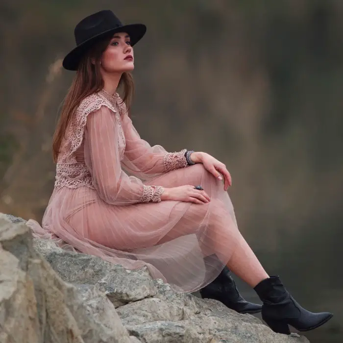 A woman wears black cowboy boots and a long dress
