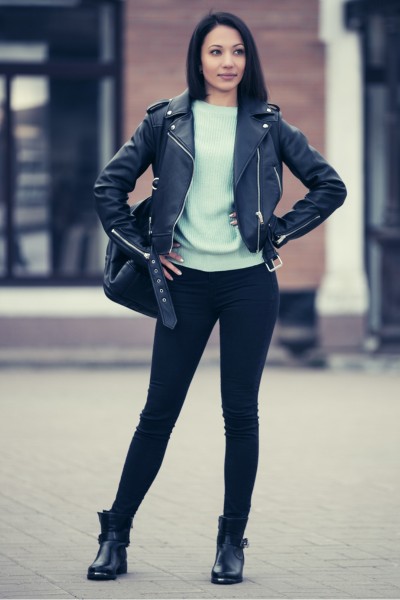 A woman wears black cowboy boots, jeans and a coat