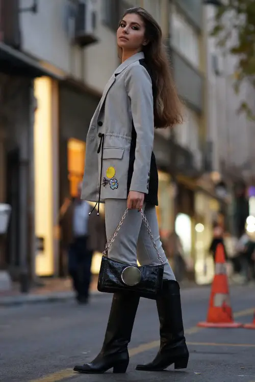 A woman wears black cowboy boots with a suit