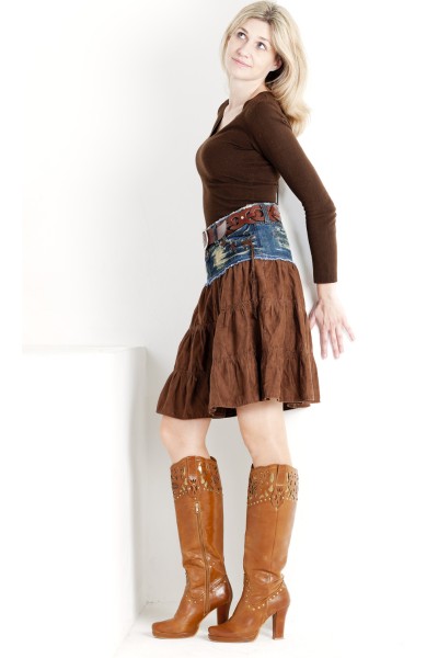 A woman wears brown boots, long sleeves top and skirt