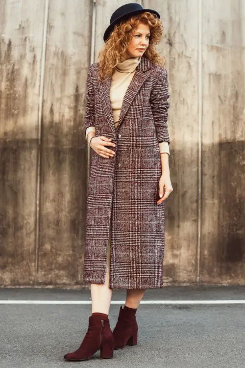 A woman wears brown cowboy boots with long coat