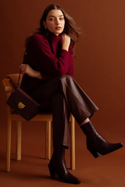 A woman wears brown cowboy boots with red sweater and leather pants
