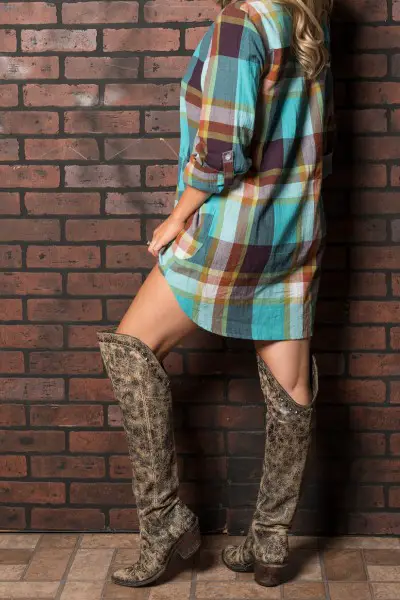 A woman wears cowboy boots with a plaid dress