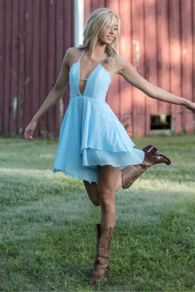 A woman wears cowboy boots with airy dress