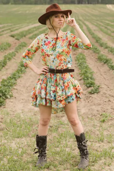 A woman wears cowboy boots with floral layered dress