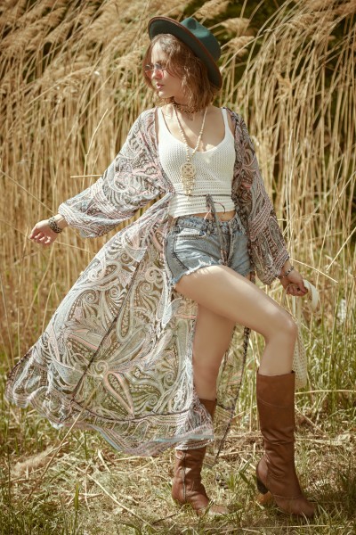 A woman wears cowboy boots with shorts, a tank and a long light coat