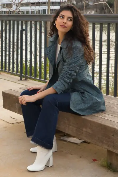 A woman wears jeans with white cowboy boots, white tee and a coat