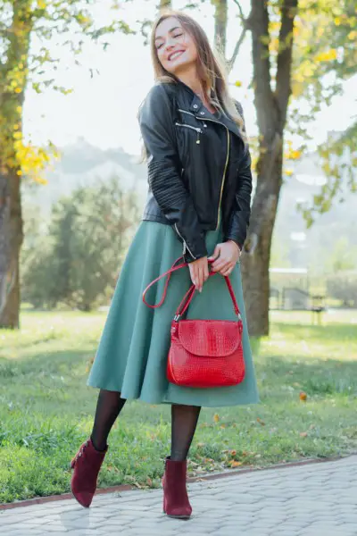 A woman wears red cowboy boots with black coat and dress