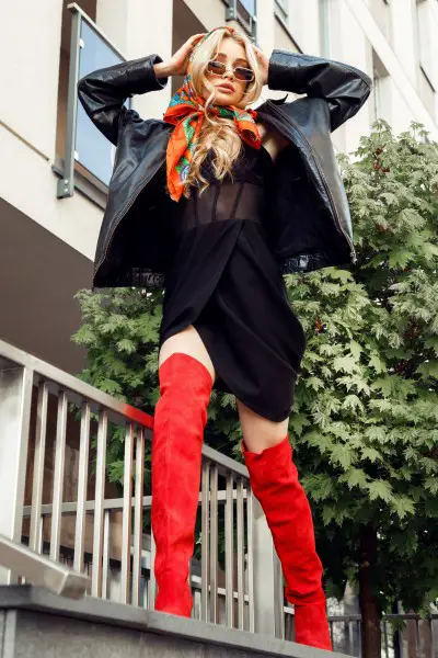 A woman wears red cowboy boots with black dress and black coat
