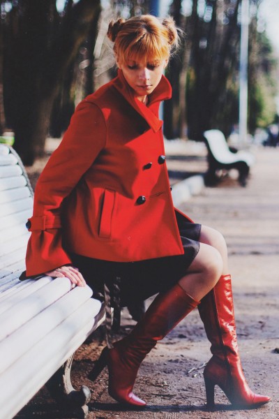A woman wears red cowboy boots with red coat and black dress