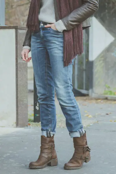 A woman wears short boots with jeans and leather jacket