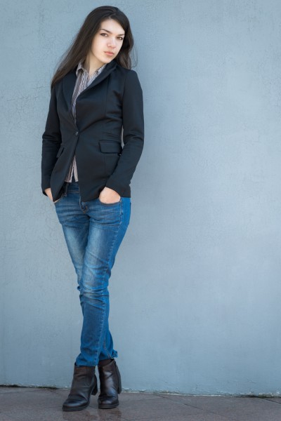 A woman wears short boots with jeans, plaid t shirt and blazer