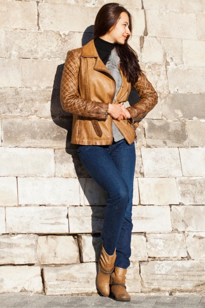 A woman wears short brownboots with jeans and leather jacket