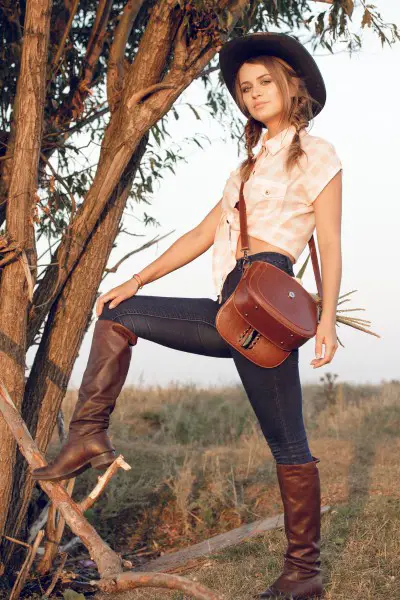 A woman wears skinny jeans with plaid blouse and a pair of leather cowboy boots.