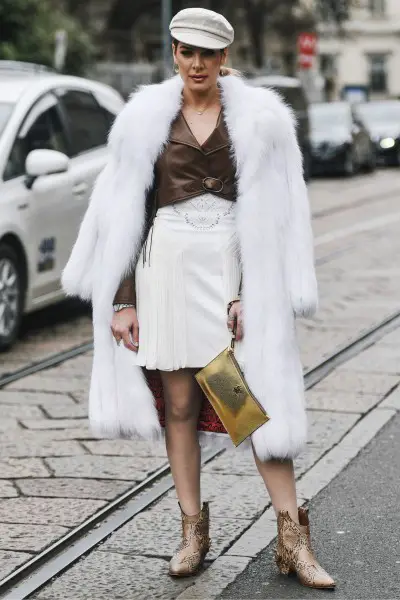 A woman wears snakeskin ankle cowboy boots with white skirts and brown shirt