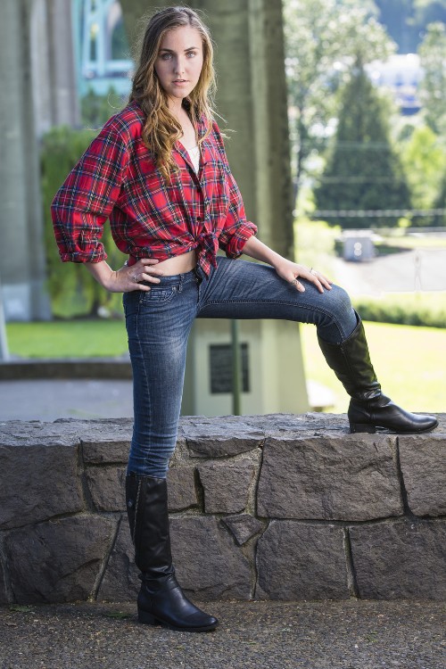 A woman wears tall cowboy boots with jeans and a plaid blouse