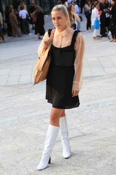 A woman wears white cowboy boots with a sheer dress