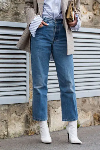 A woman wears white cowboy boots with jeans, plaid blazer and stripped shirt