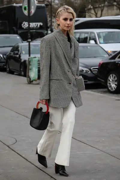 A woman wears white jeans with black ankle cowboy boots and a blazer