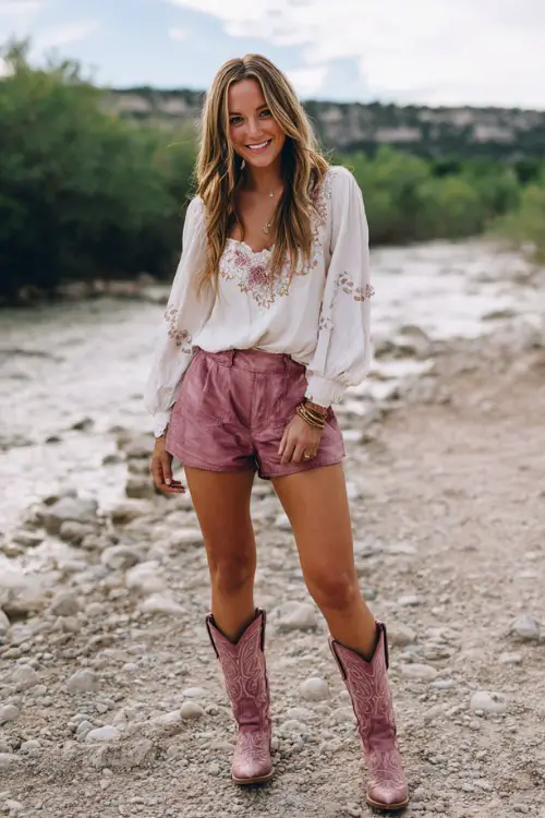 a woman wears a white blouse with pink embroidery, pink shorts and pink cowboy boots