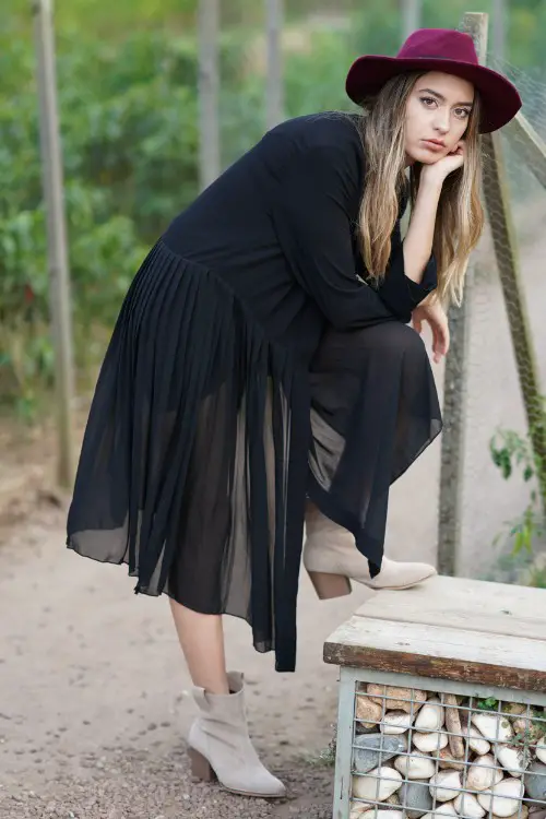 A woman wears ankle cowboy boots with a black dress