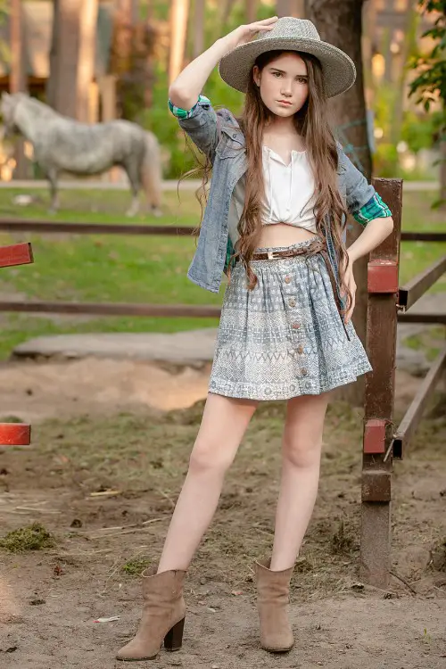 A woman wears ankle cowboy boots with coat and light top