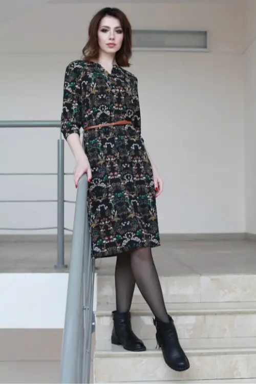 A woman wears black ankle cowboy boots with floral dress