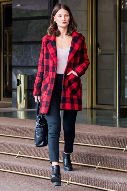 A woman wears black cowboy boots with black pants and plaid coat