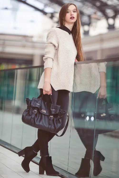 A woman wears black cowboy boots with sweater and black pants