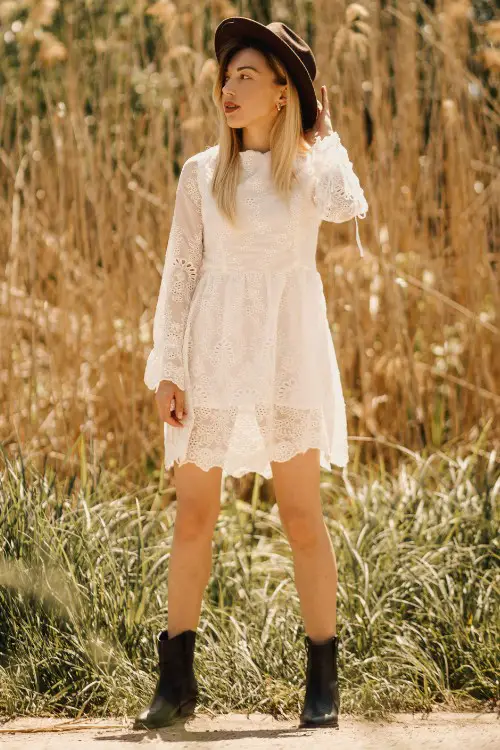 A woman wears black cowboy boots with white dress