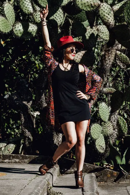 A woman wears black dress with brown cowboy boots