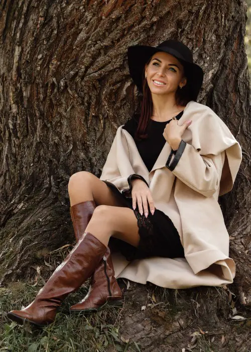 A woman wears black dress with brown cowboy boots