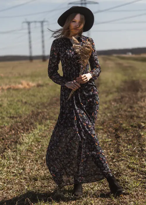 A woman wears black floral dress with cowboy boots