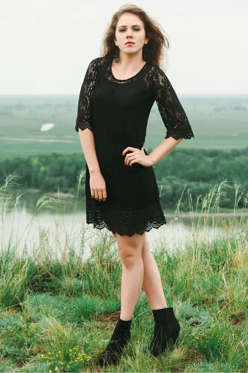 A woman wears black lace dress with cowboy boots