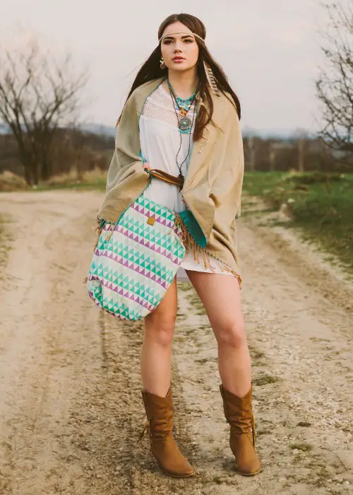 A woman wears boho dress, coat with brown cowboy boots
