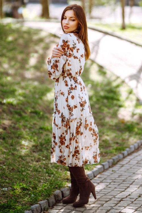 A woman wears brown cowboy boots with a dress