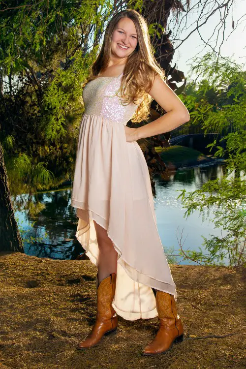 A woman wears brown cowboy boots with a high lơ dress