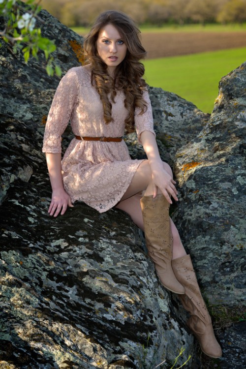 A woman wears brown cowboy boots with a lace dress