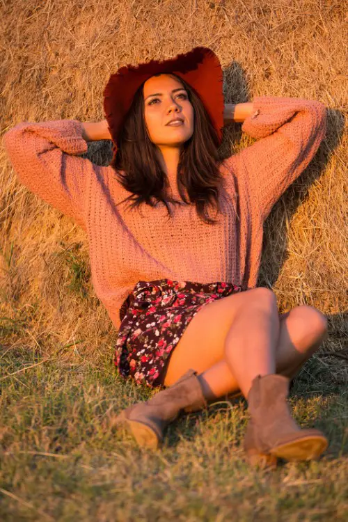 A woman wears brown cowboy boots with a skirt and a sưeater