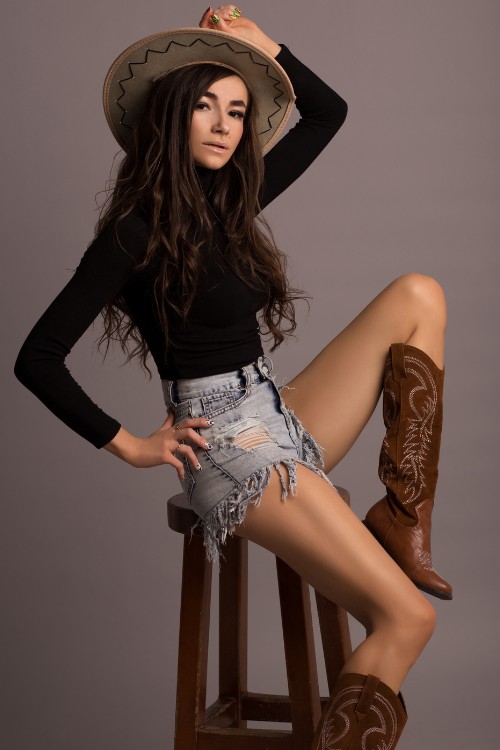 A woman wears brown cowboy boots with fitted black top