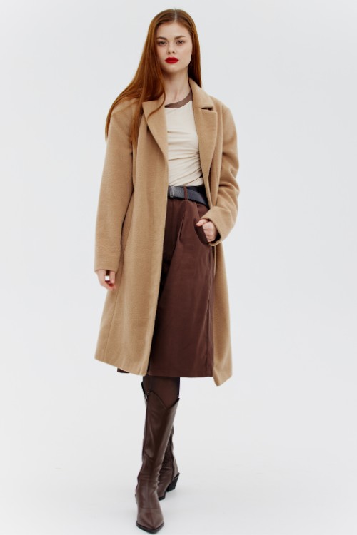 A woman wears brown cowboy boots with long coat and culottes