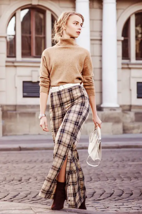 A woman wears brown cowboy boots with plaid skirt and sweater