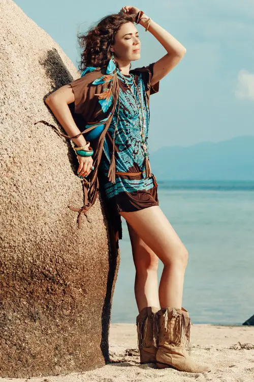 A woman wears brown cowboy boots with shorts and a boho shirt