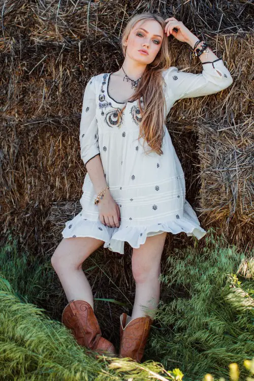 A woman wears brown cowboy boots with white dress