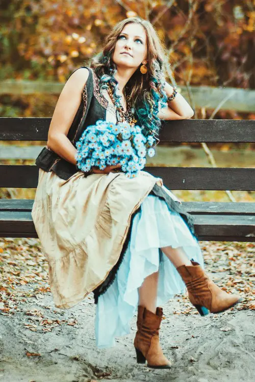 A woman wears cowboy boots with a complex boho dress