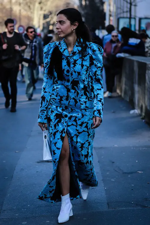 A woman wears cowboy boots with a dress with high slit