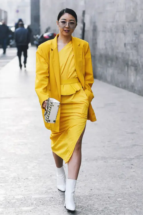 A woman wears cowboy boots with a yellow dress with high slit