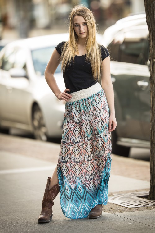 A woman wears cowboy boots with boho skirt and a black top