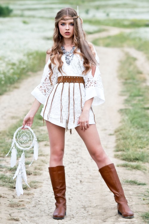 A woman wears cowboy boots with lace shorts, a top and a leather belt